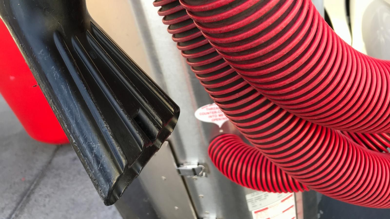 A red and black hose is attached to a car vacuum cleaner.