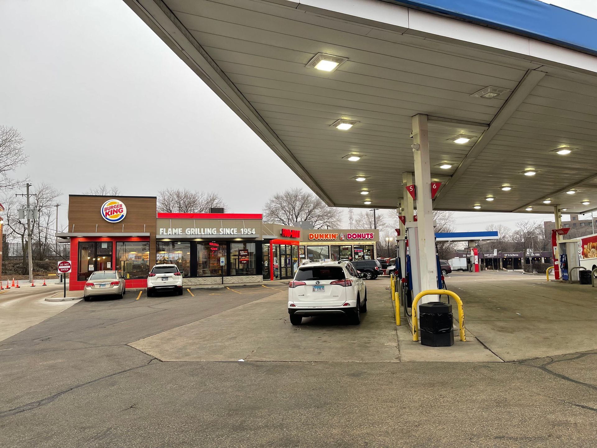A gas station with a burger king restaurant in the background.