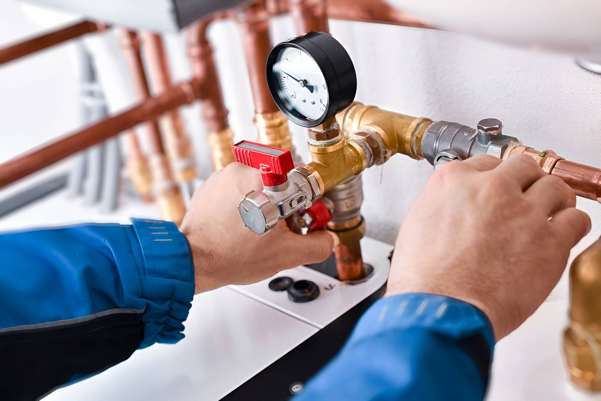 A Plumber Is Working On A Water Heater With Copper Pipes And A Pressure Gauge — Christians Plumbing in Emerald, QLD