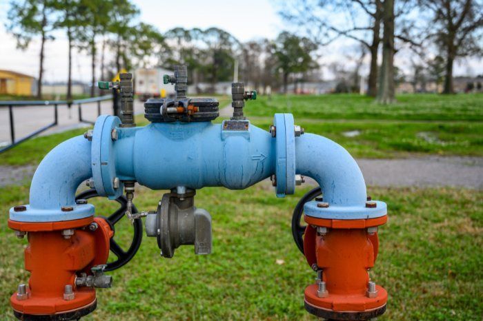 A Blue And Orange Water Pipe Is Sitting On Top Of A Lush Green Field — Christians Plumbing in Emerald, QLD