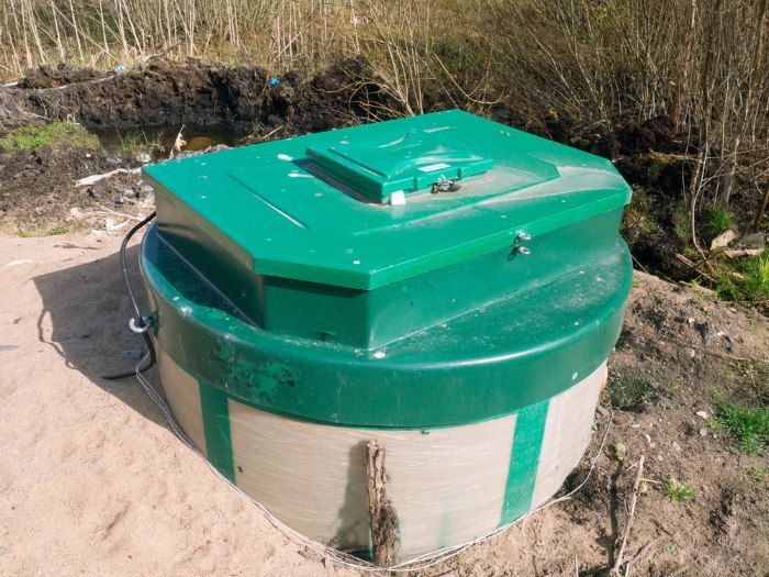 A Green And White Container Is Sitting In The Dirt — Christians Plumbing in Emerald, QLD