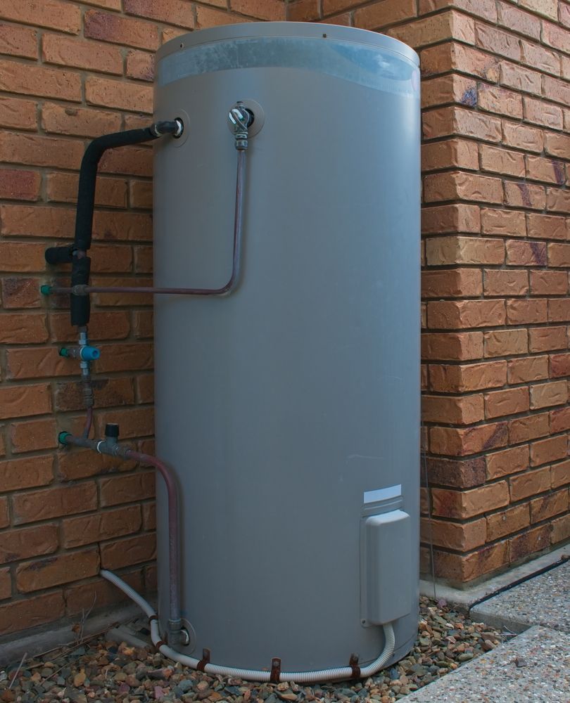 A Gray Water Heater Is Attached To A Brick Wall — Christians Plumbing in Emerald, QLD