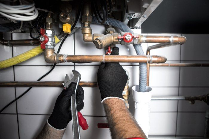 A Man Is Working On A Pipe With A Wrench — Christians Plumbing in Emerald, QLD