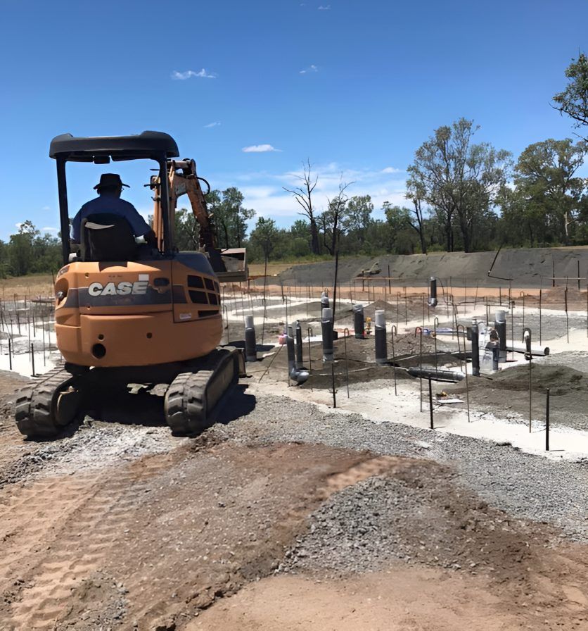 A Man Is Driving A Case Excavator On A Dirt Road — Christians Plumbing in Emerald, QLD
