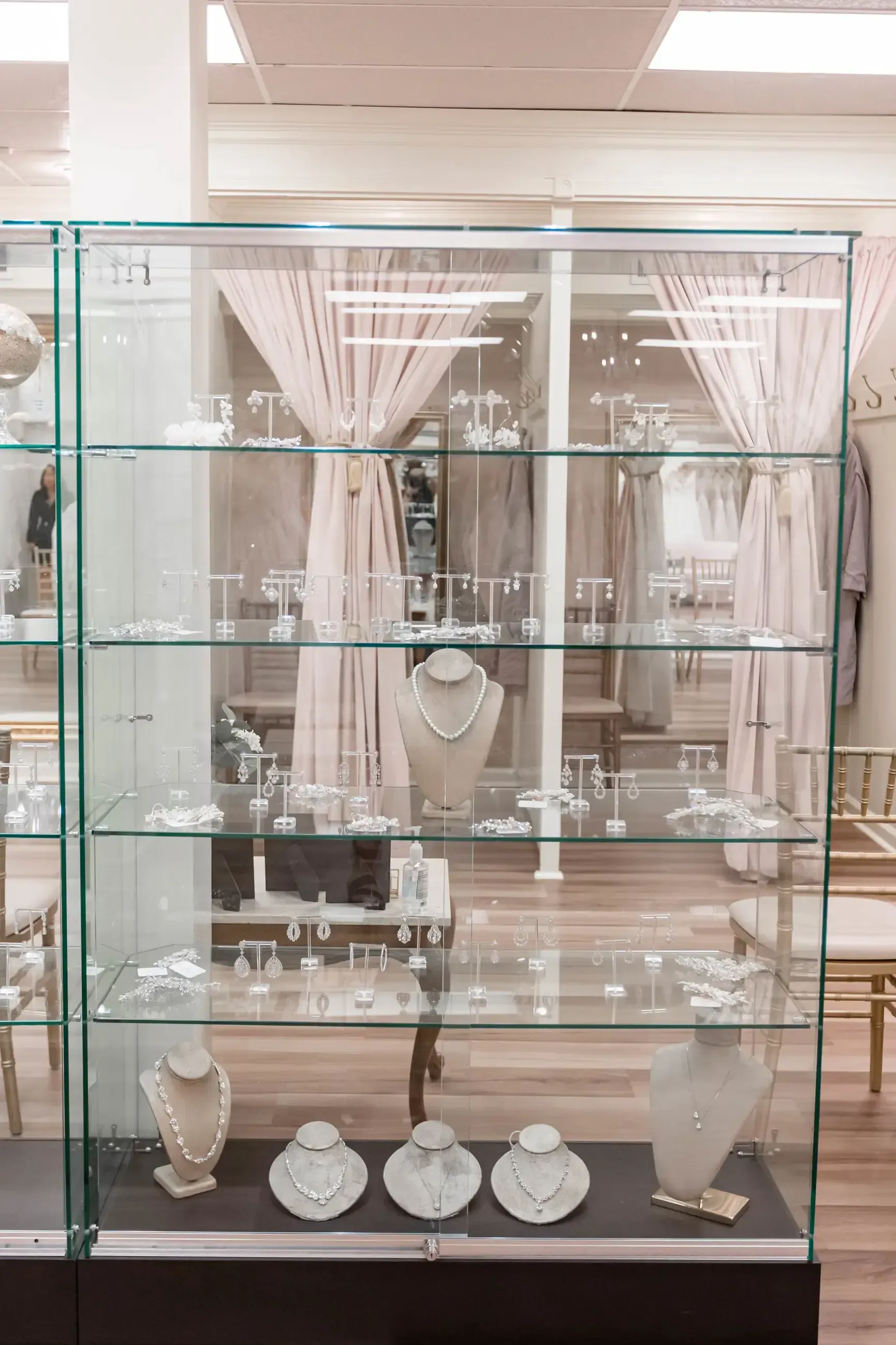 Glass display case filled with jewelry, including necklaces and earrings, in a store setting.