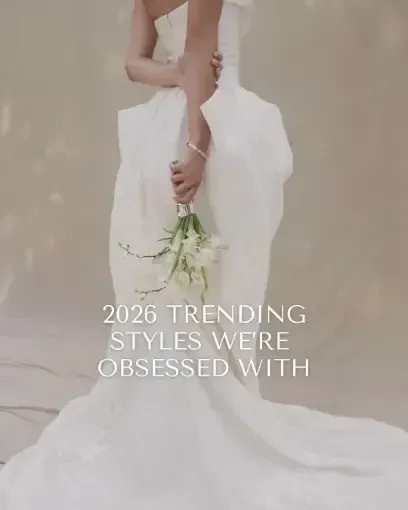 Woman in a white wedding gown, holding a bouquet. Text overlay reads "2026 TRENDING STYLES WE'RE OBSESSED WITH."