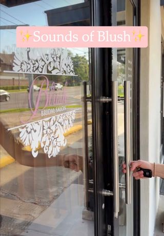 Hand opening a glass door with pink “✨Sounds of Blush✨” signage and white floral decals