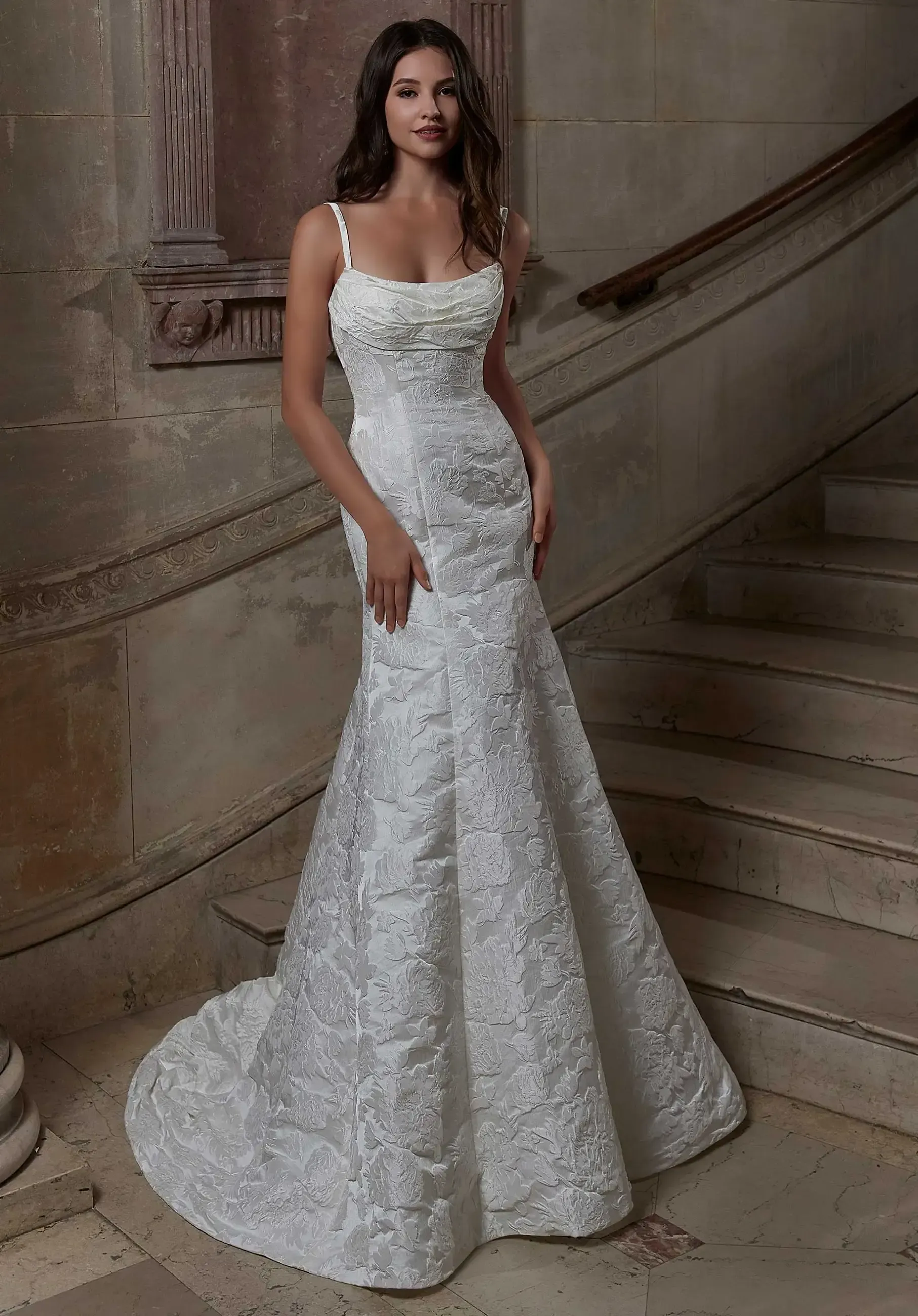 Woman in white textured wedding dress on grand staircase.