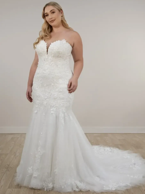 Woman in a white strapless mermaid-style wedding dress, with lace details and a long train.