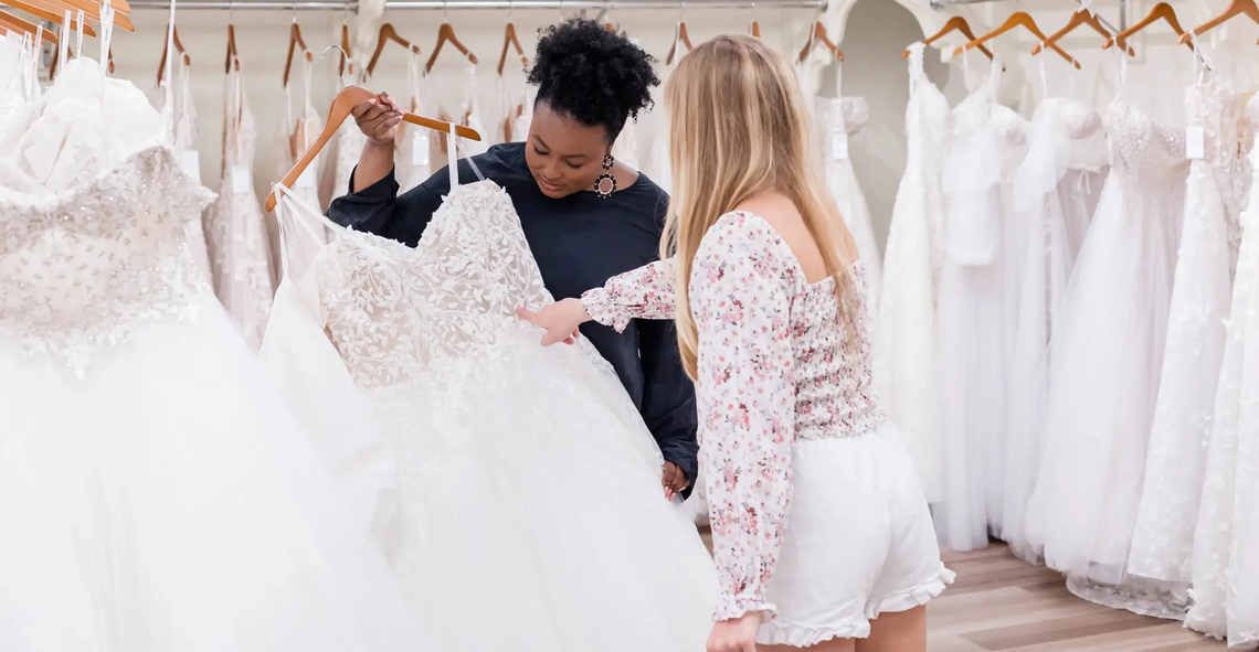 Exterior of a bridal shop called Blush, with wedding dresses in the windows and a sign above.