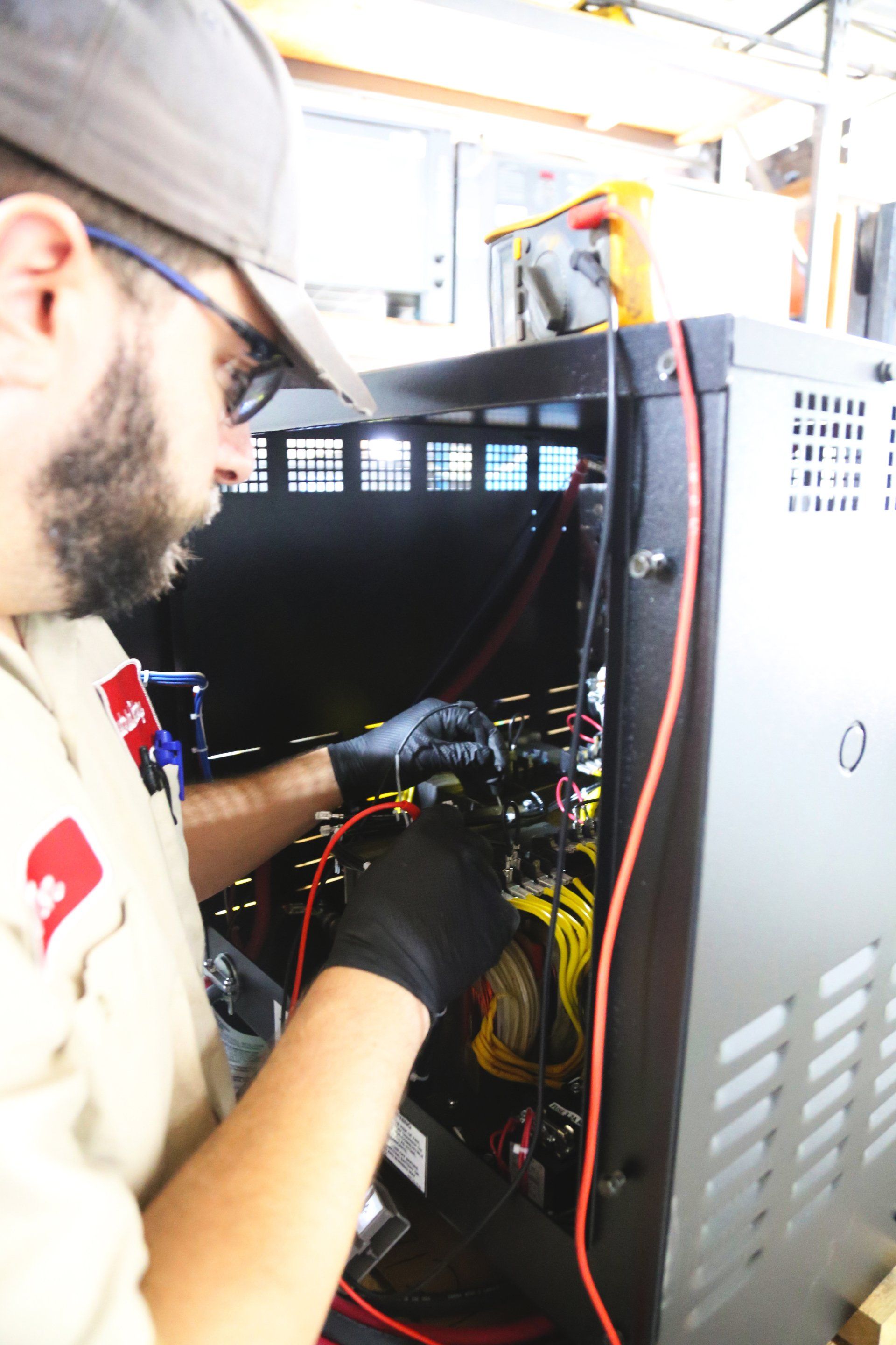 A man wearing a hat and gloves is working on a machine