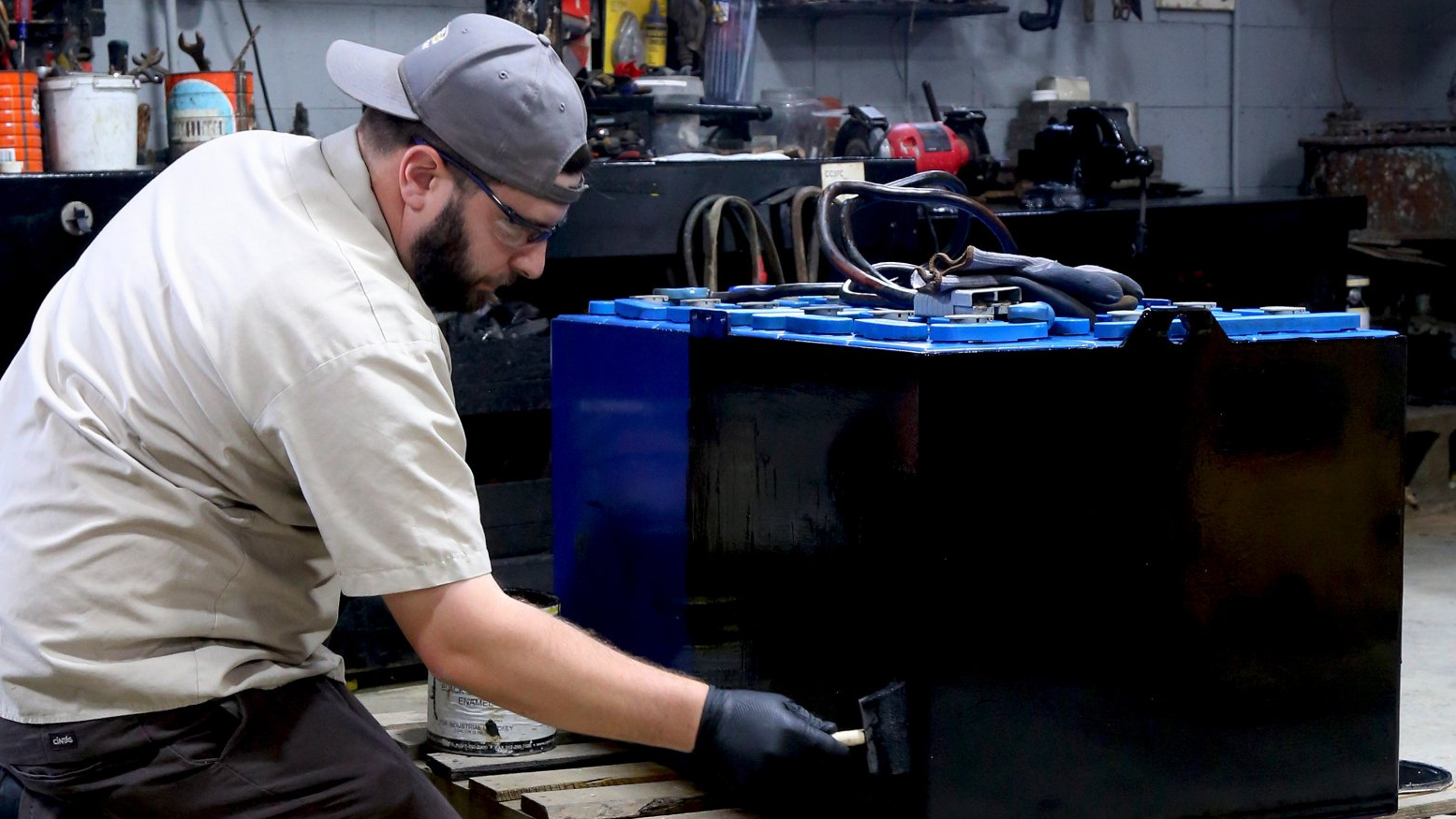 A man is working on a battery in a garage.