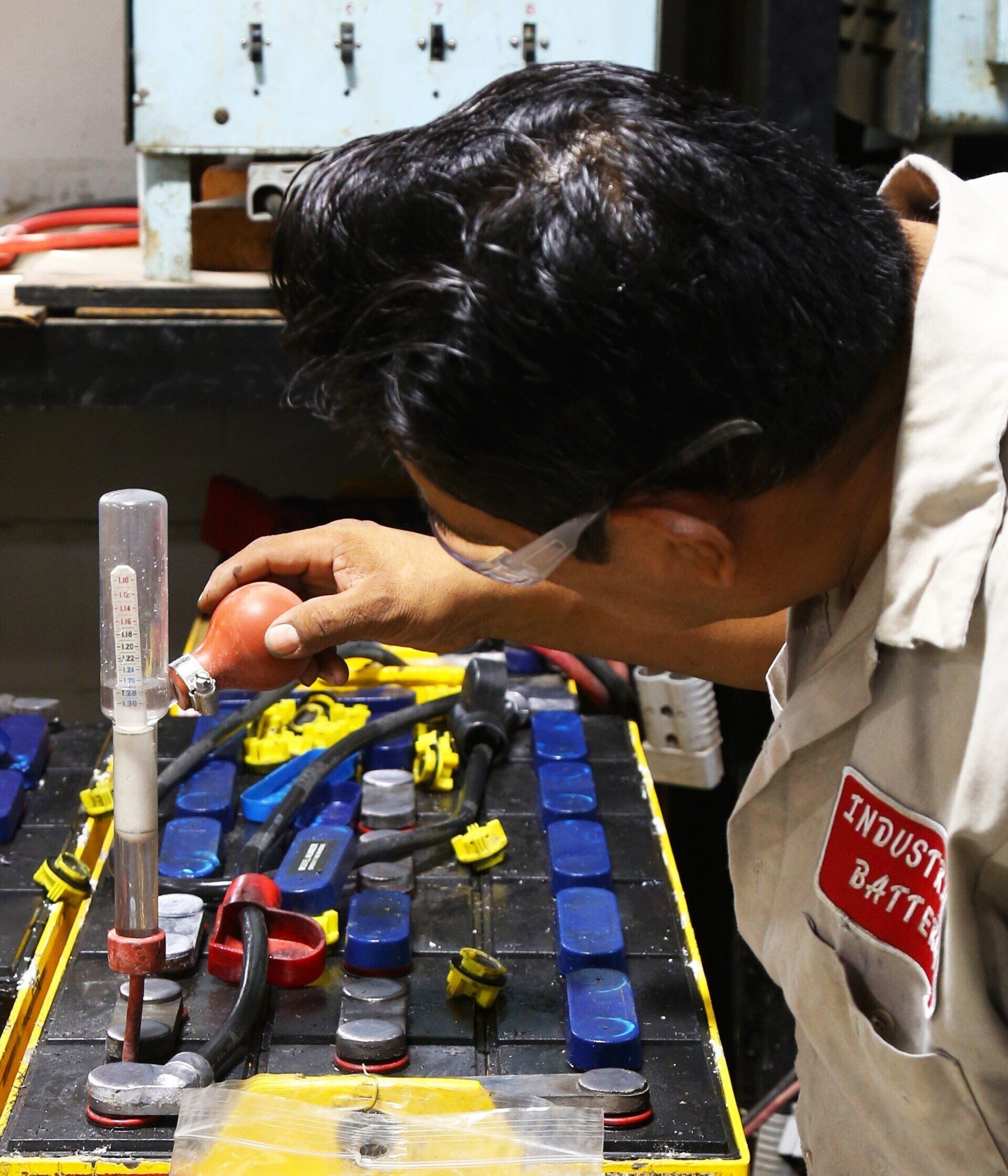 A man wearing a jacket that says industrial battery is working on a battery