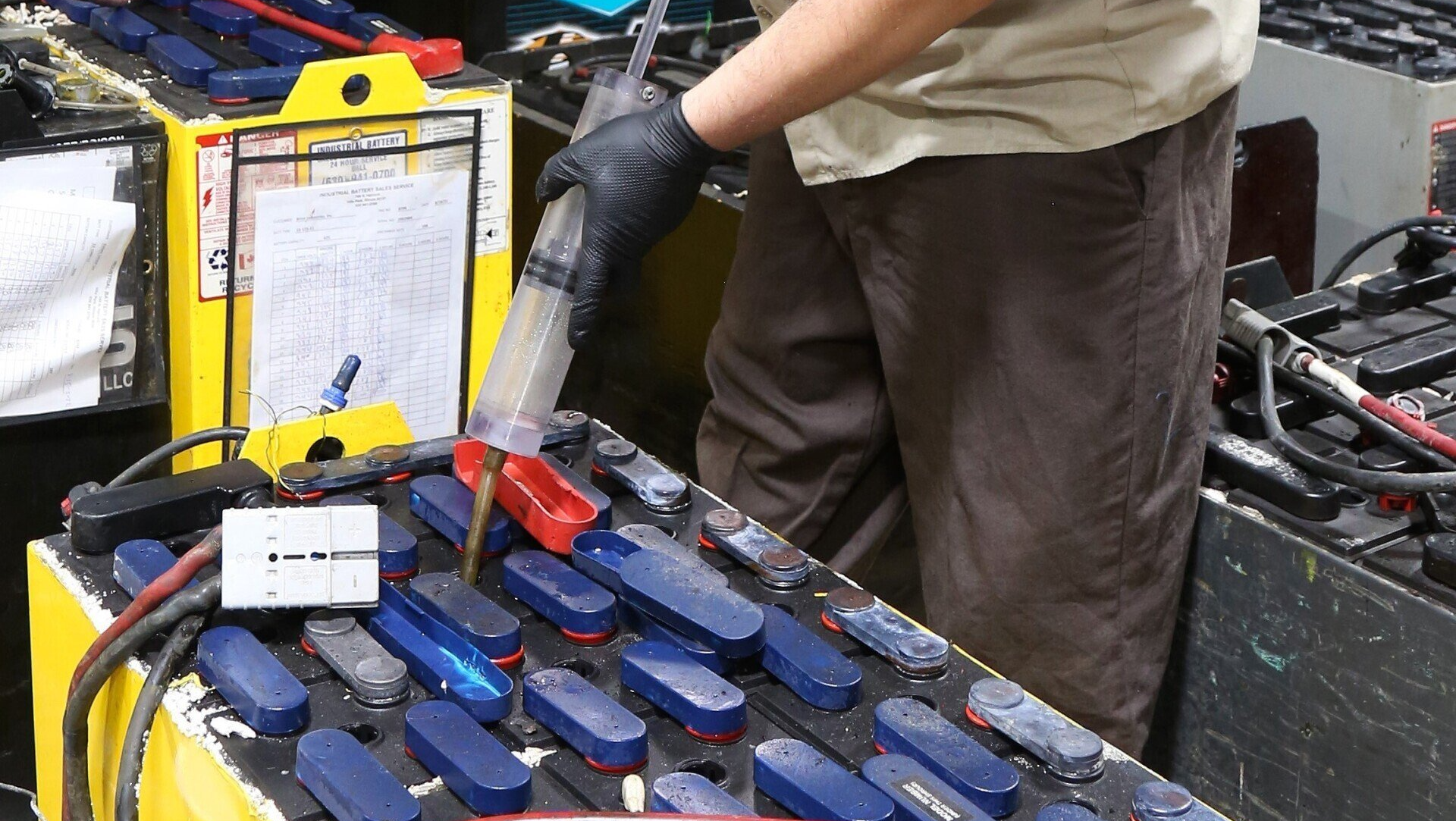 A man is cleaning a battery with a vacuum cleaner.