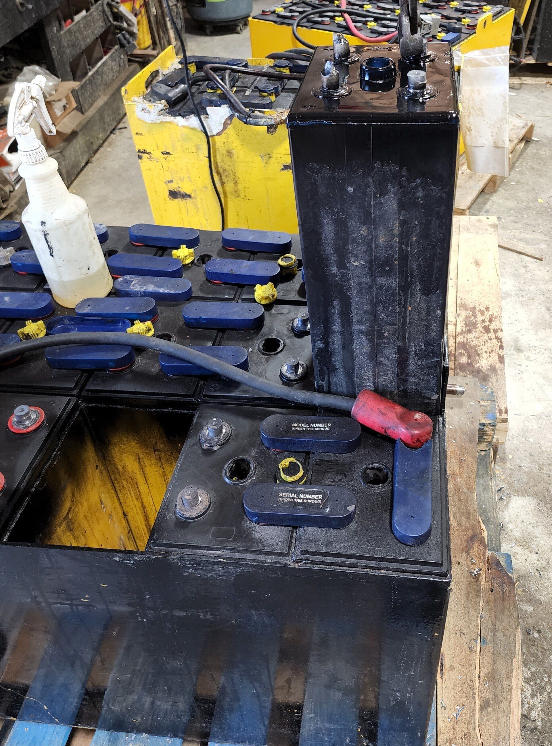 A bunch of batteries are sitting on top of a wooden pallet.