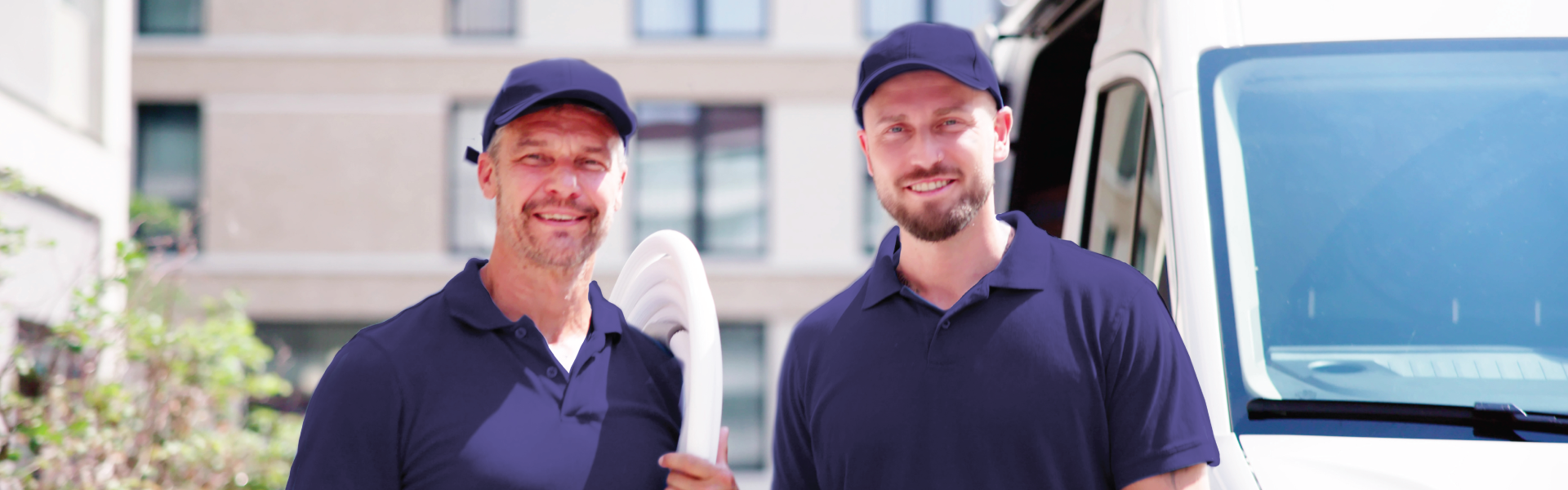 Two delivery men are standing next to each other in front of a truck.