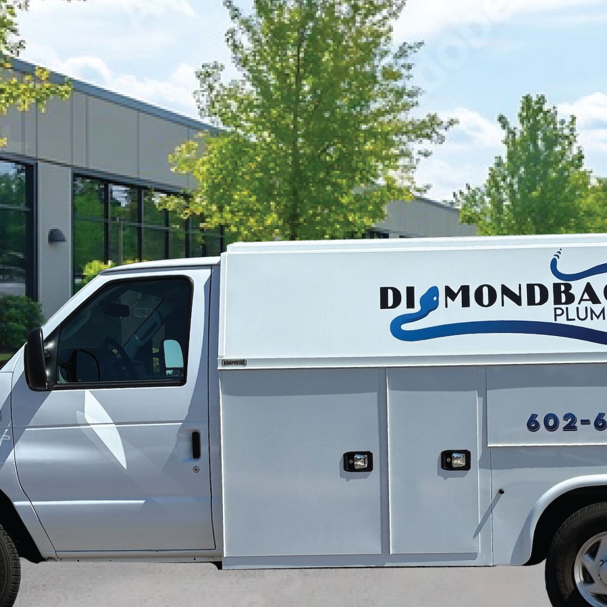 A diamondback plumbing truck is parked in front of a building