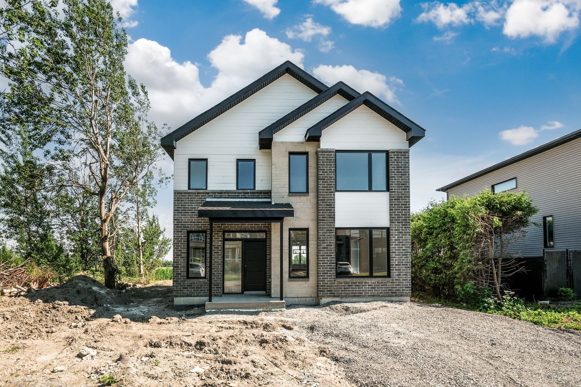Une grande maison avec beaucoup de fenêtres est située au sommet d'une colline de terre.