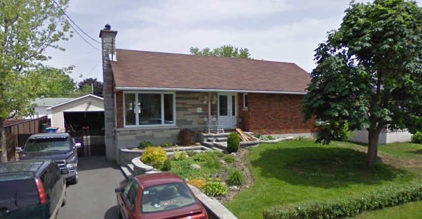 Une maison avec une voiture rouge garée devant