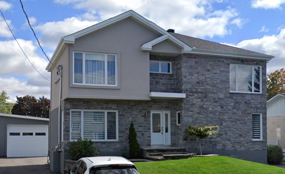 Une voiture est garée devant une grande maison en briques.