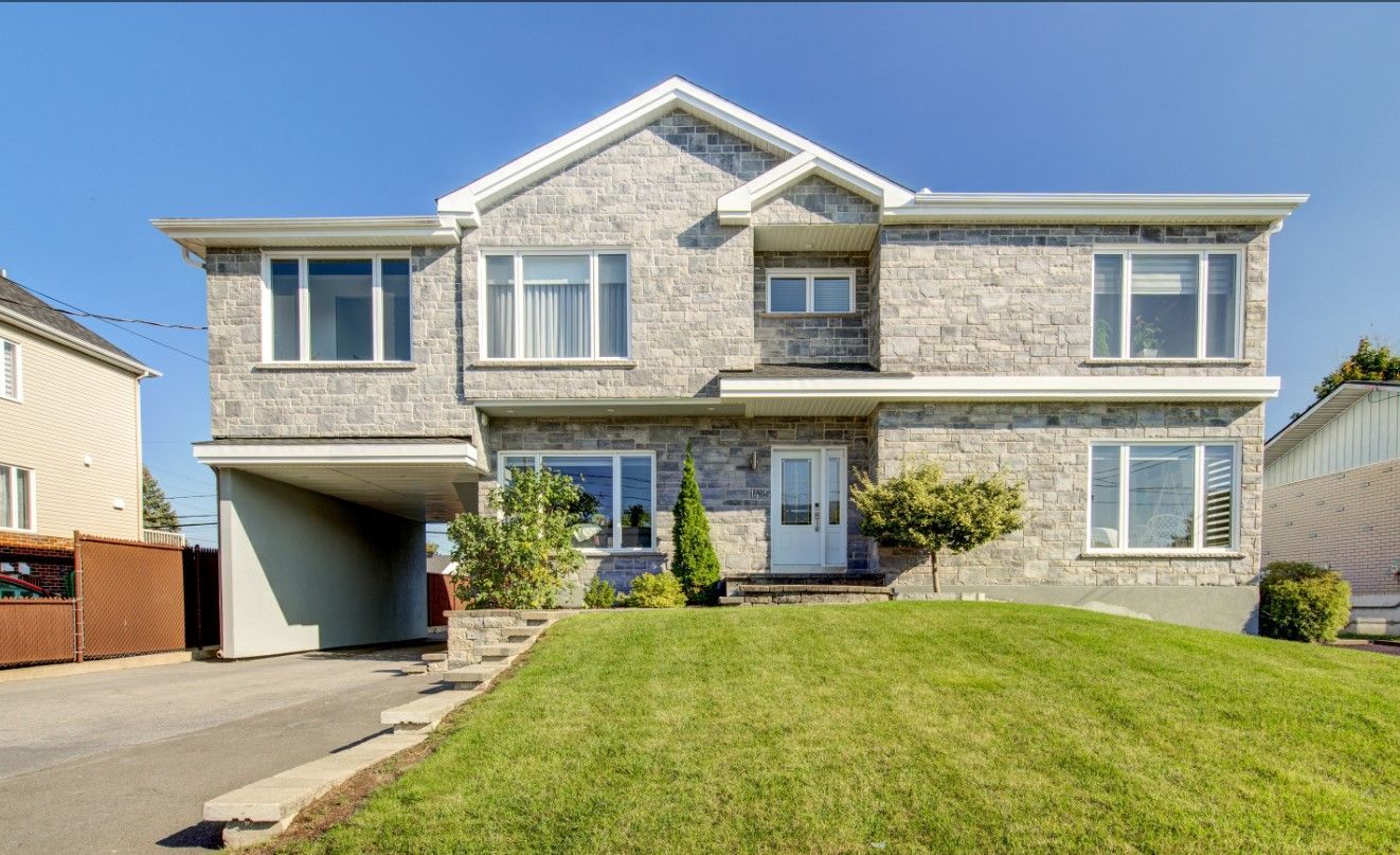 Une grande maison en briques avec une pelouse verte luxuriante devant elle.