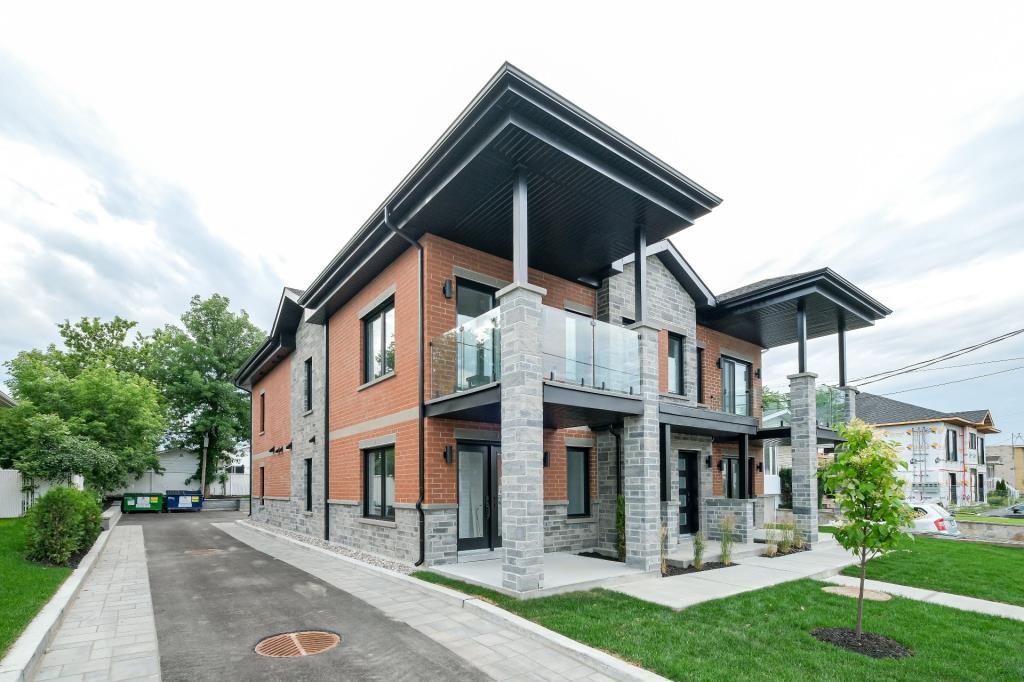 Un grand bâtiment en briques avec beaucoup de fenêtres se trouve au sommet d'une pelouse verte luxuriante.