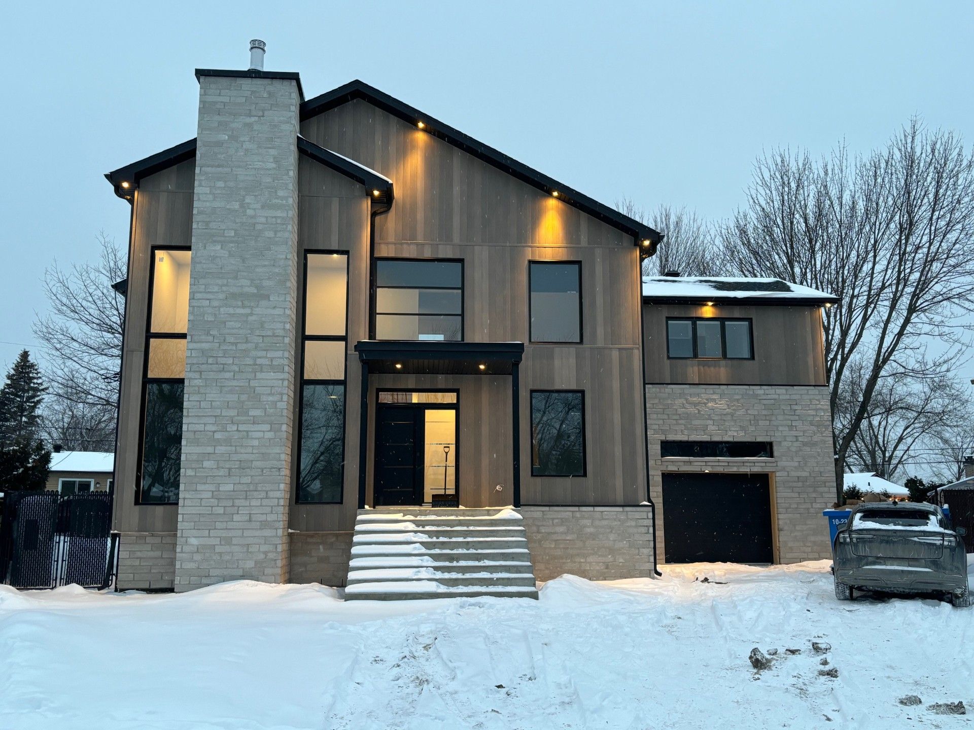 Une grande maison avec une voiture garée devant sous la neige.
