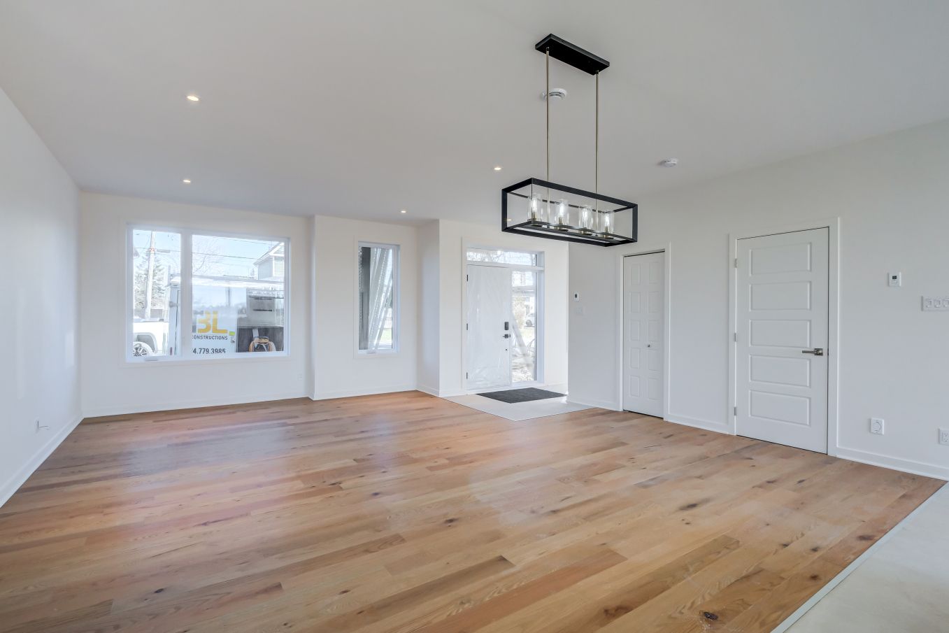 Un salon vide avec du parquet et des murs blancs.