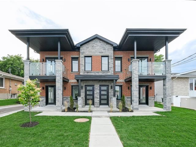 Une grande maison en brique et en pierre avec une pelouse verte luxuriante devant elle.