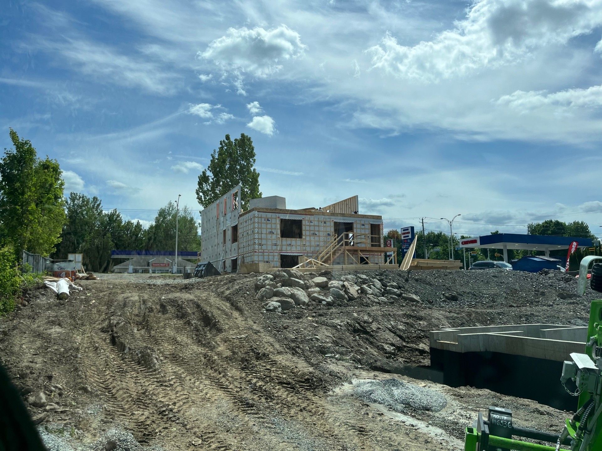 Un grand bâtiment est en construction au milieu d'un champ de terre.