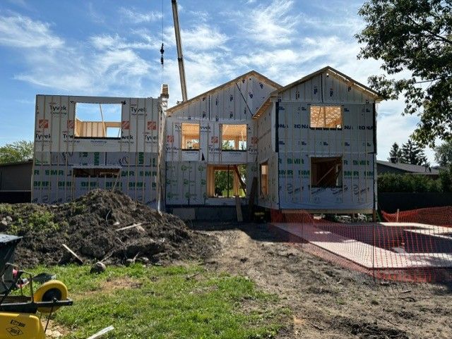 Une maison est en construction avec une grue en arrière-plan.