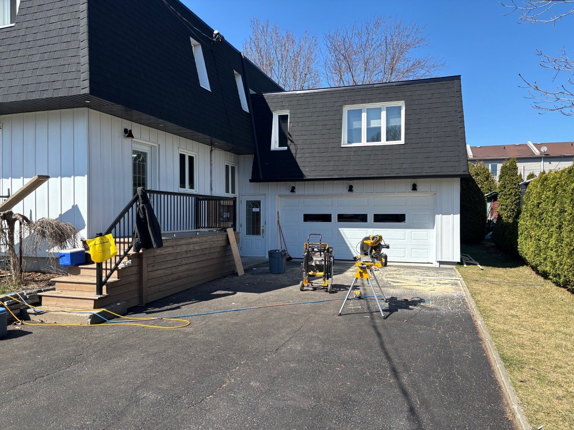 Une maison blanche avec un toit noir est en cours de rénovation.