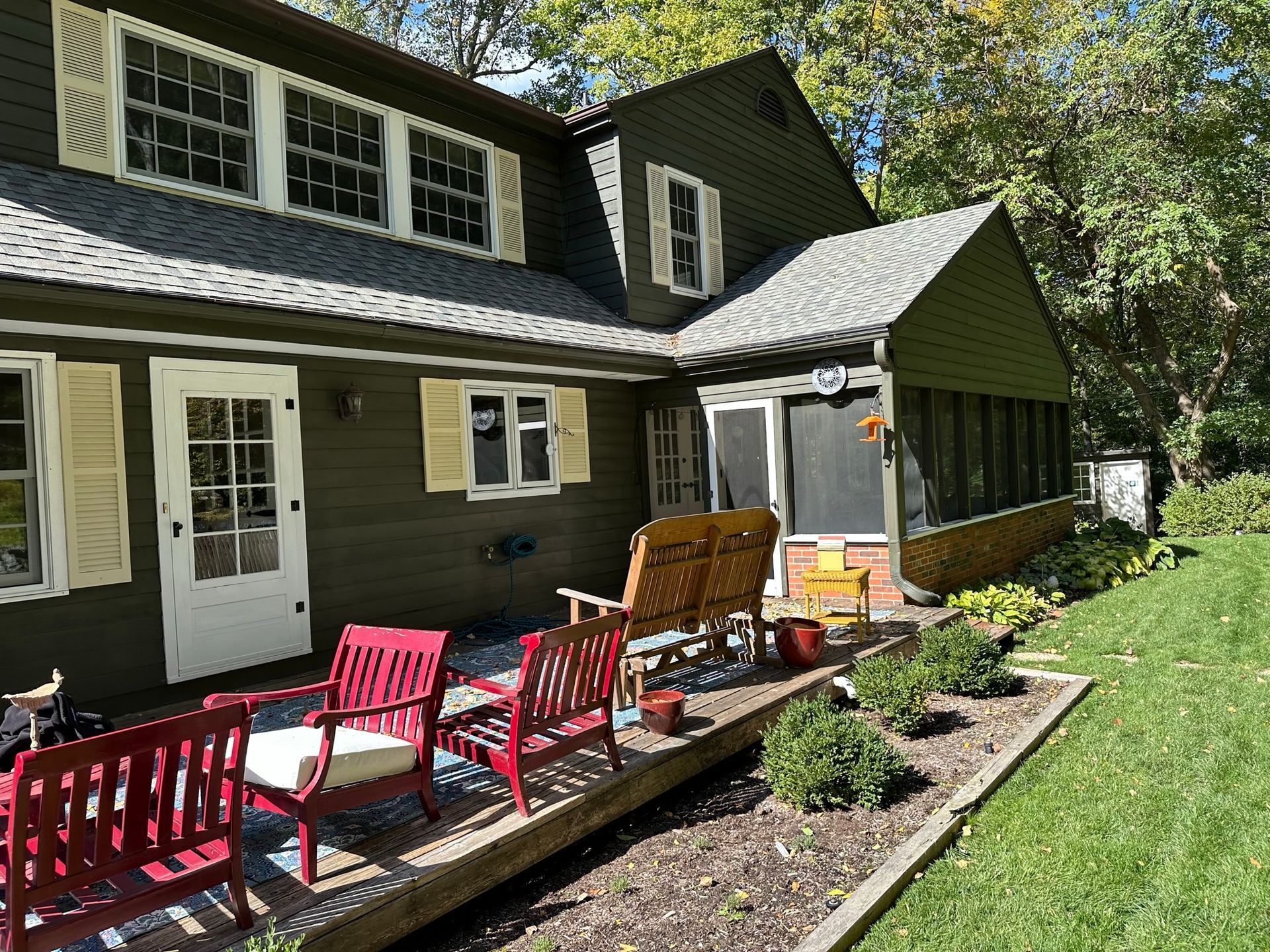 Woman in straw hat smiles, holding wine glass near a lake.
