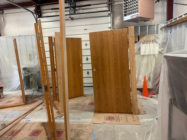 Woman in straw hat smiles, holding wine glass near a lake.
