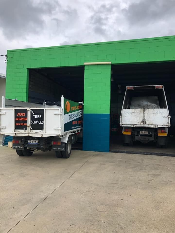 Two trucks are parked in front of a green building.