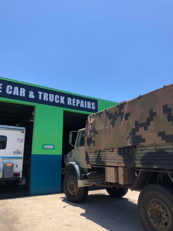 A truck is parked in front of a car and truck repair shop