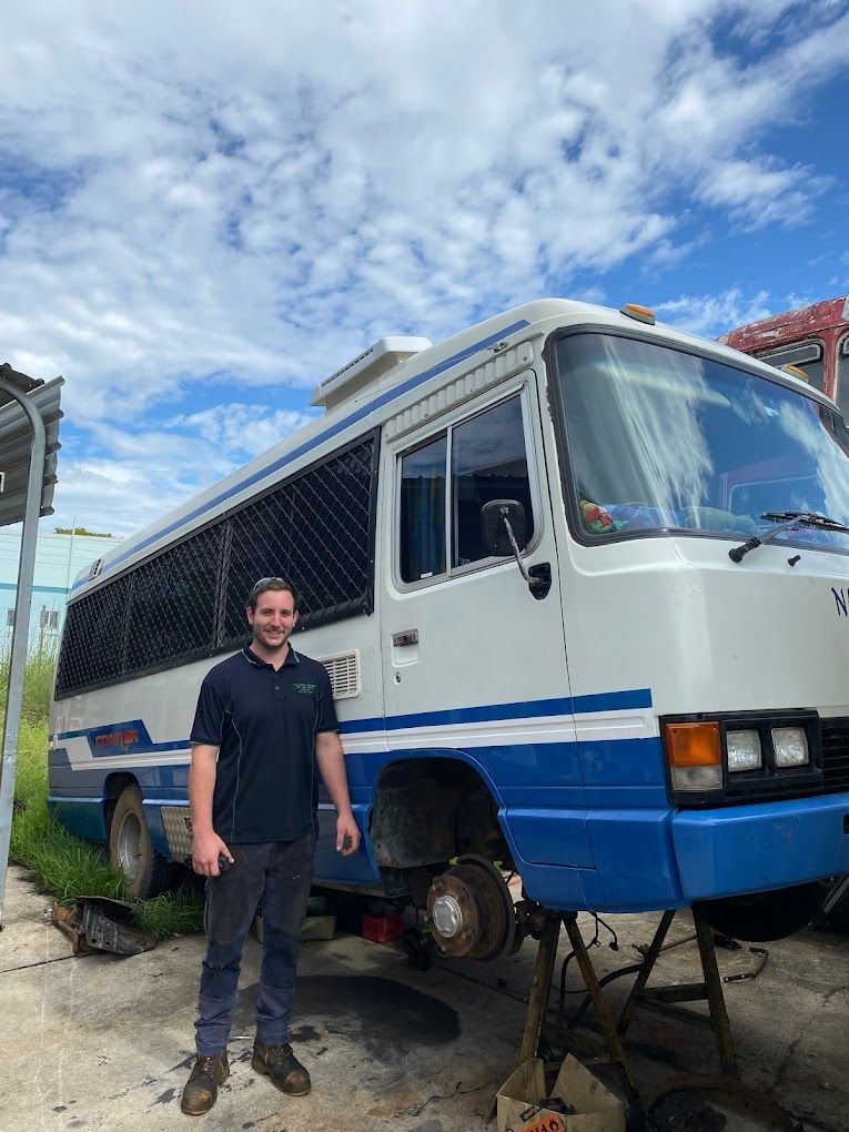 A man is standing in front of a blue and white bus.