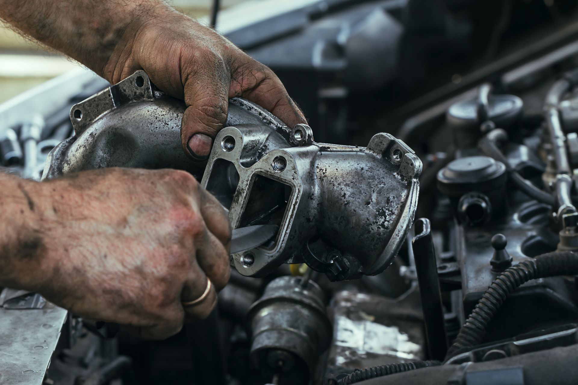 Mechanic's Hands Holding a Dark, Metallic Engine Part — Reliable Bus and Truck Repairs In Caloundra West, QLD