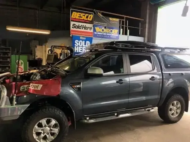 A truck with the hood open is parked in a garage.
