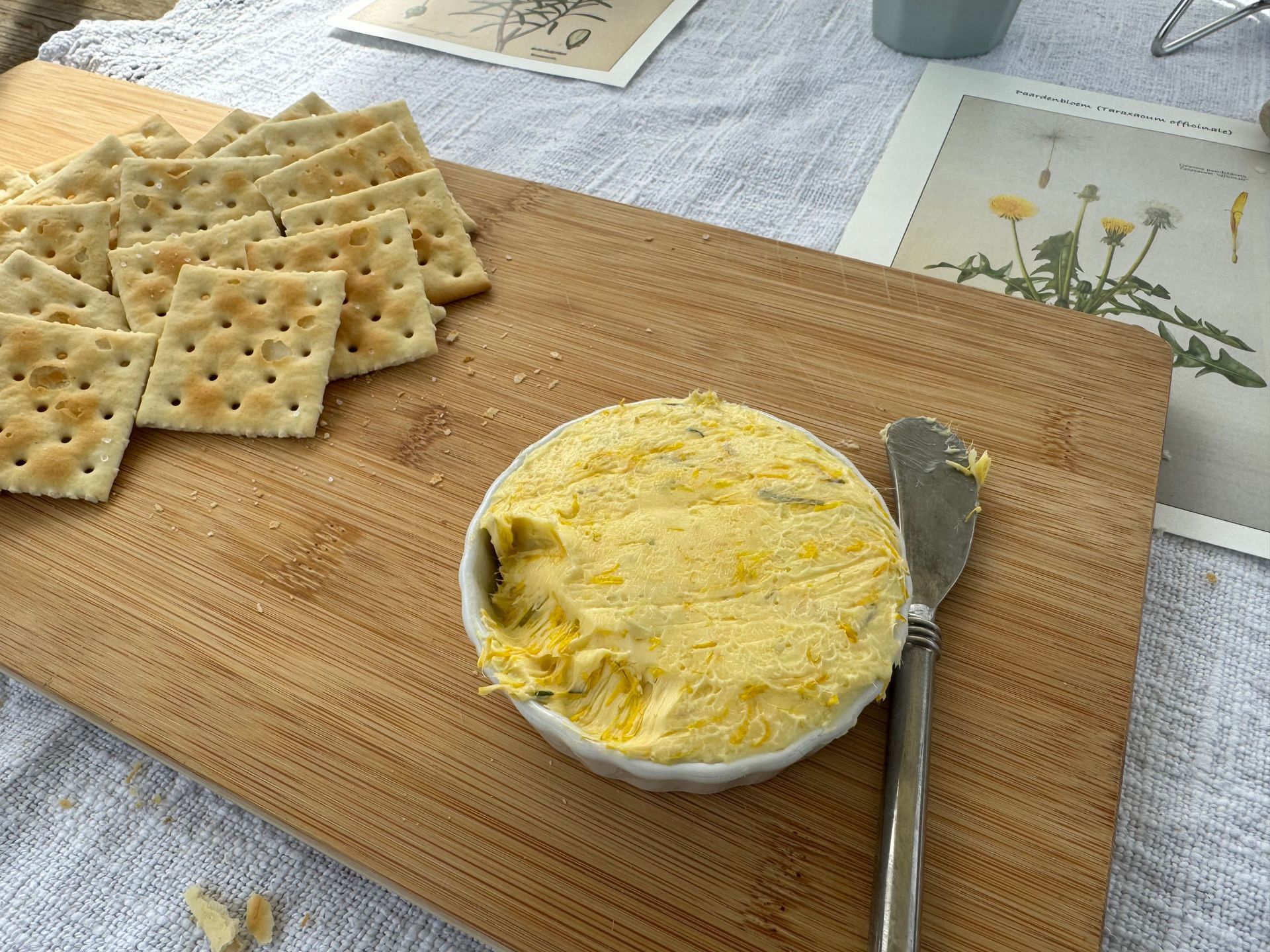 houten plank met mesje, crackers en paardenbloemboter