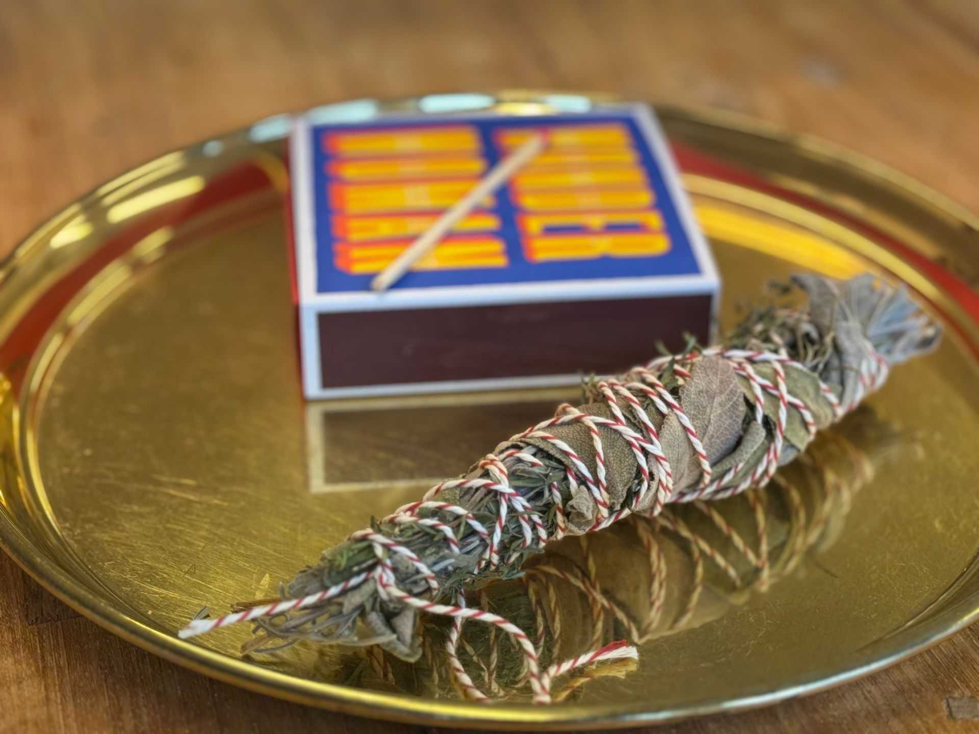 smudgestick van rozemarijn, tijm en salie op messing dienblad met lucifers