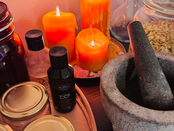 kaarsen, vijzel, kruiden en olie op een tafel