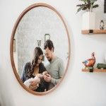 A man and woman are holding a baby in front of a mirror.