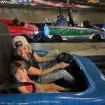 A woman and a child are riding a go kart at an amusement park.