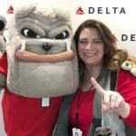 A woman is posing for a picture with a bulldog mascot.