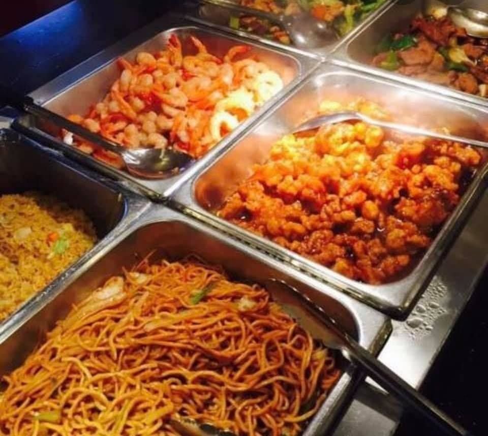 A buffet filled with a variety of food including noodles and shrimp