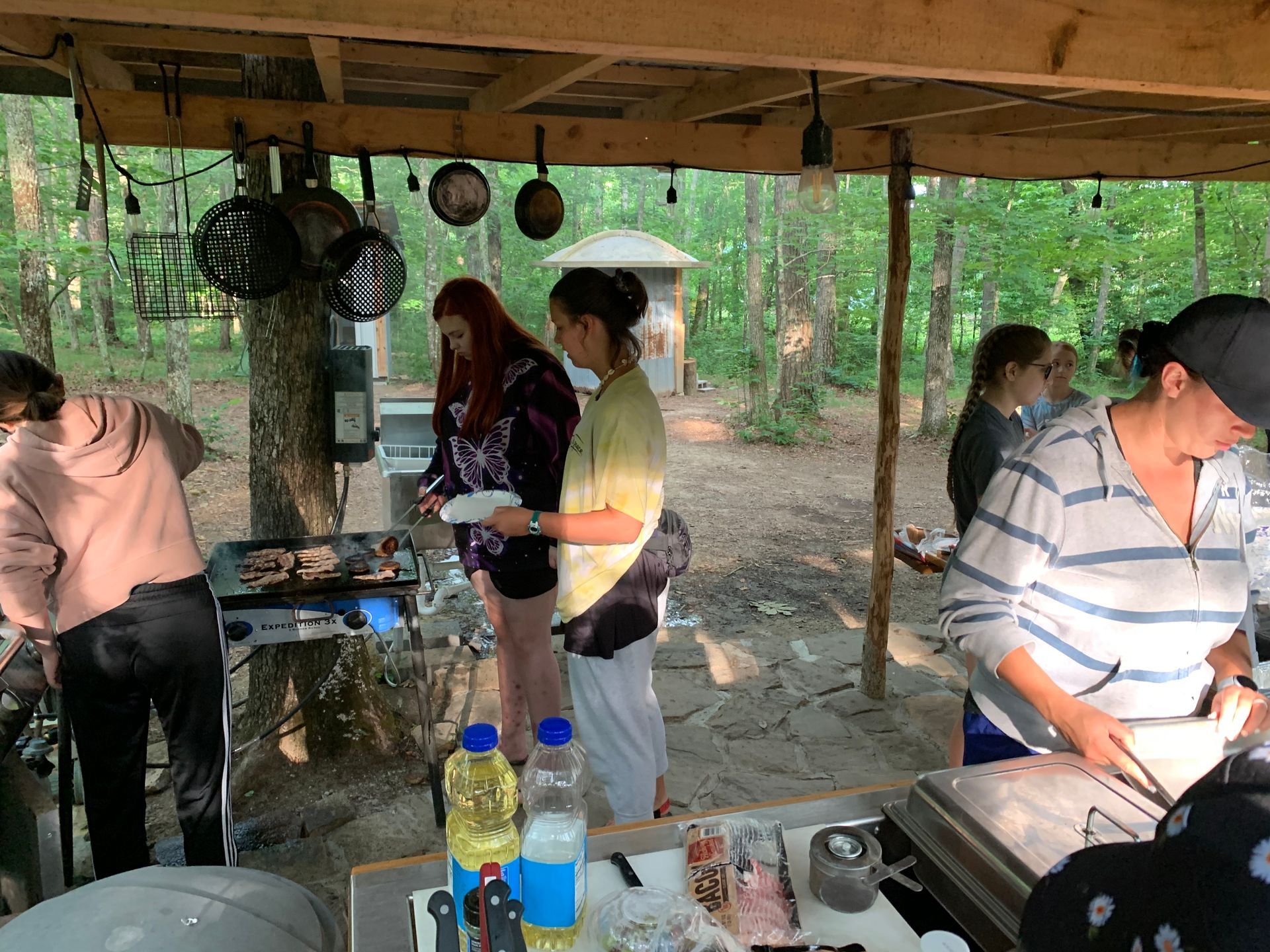 A group of people are standing around a table cooking food.