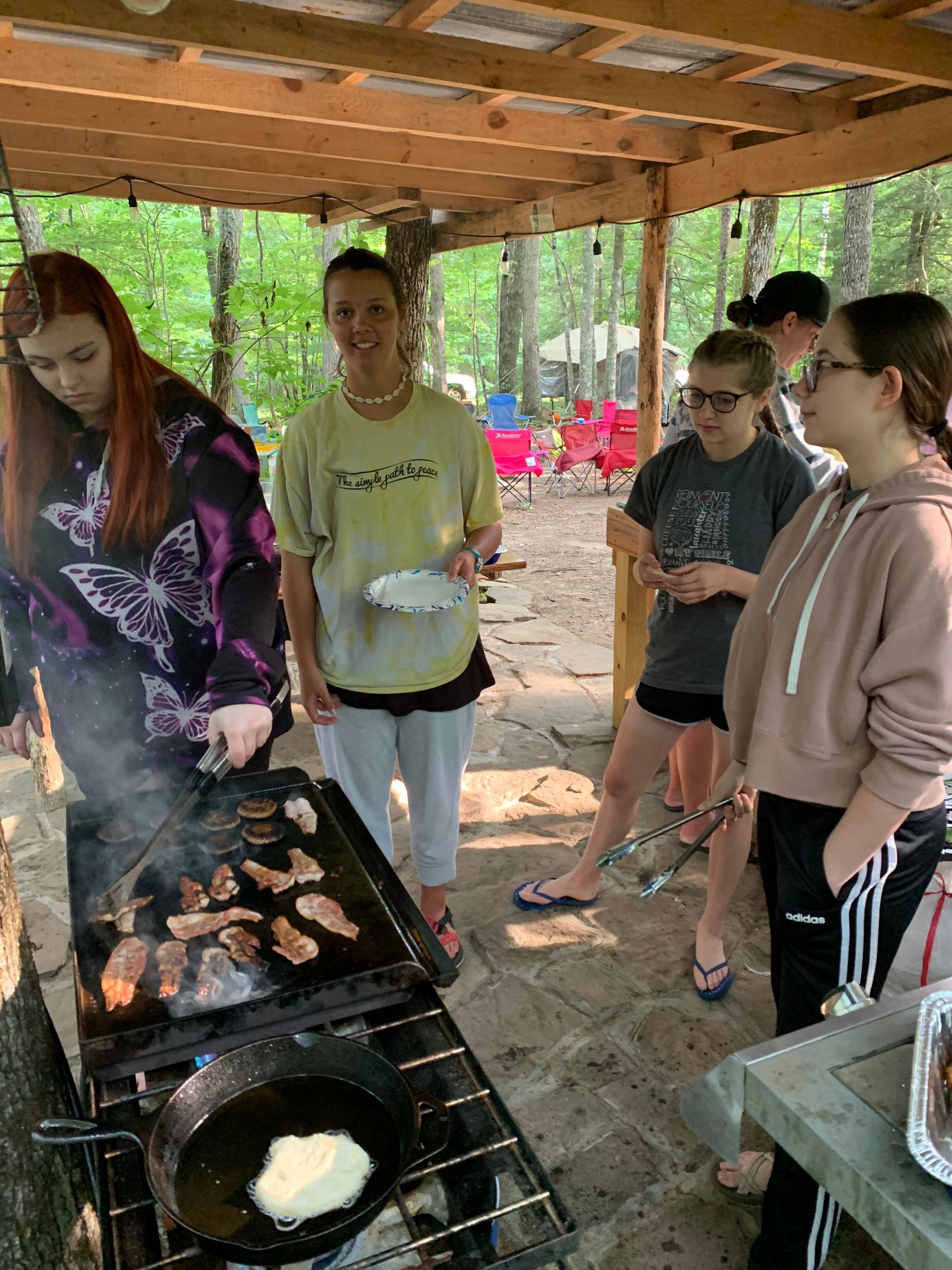 A group of people are standing around a grill cooking food.