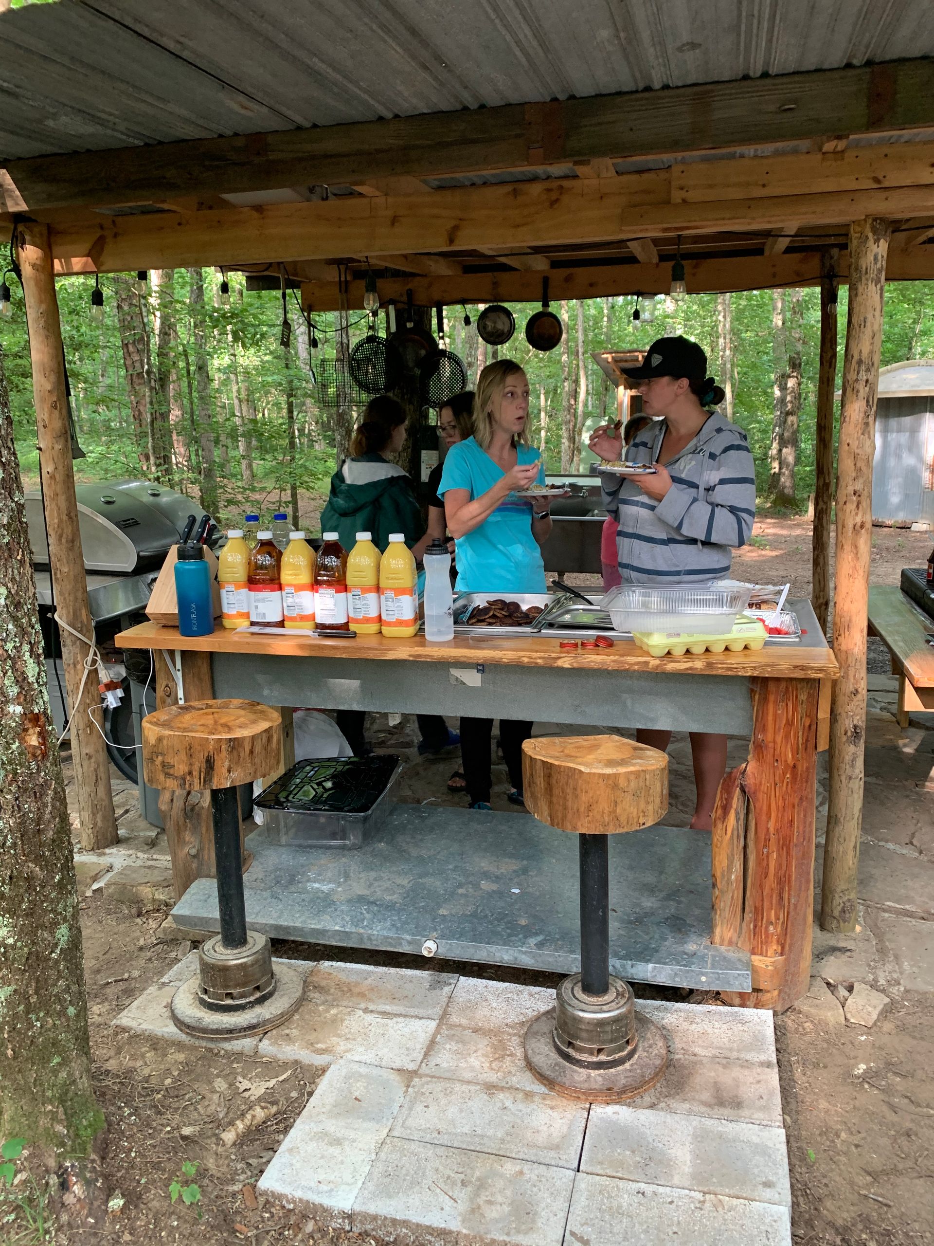 A group of people are standing around a table in the woods.