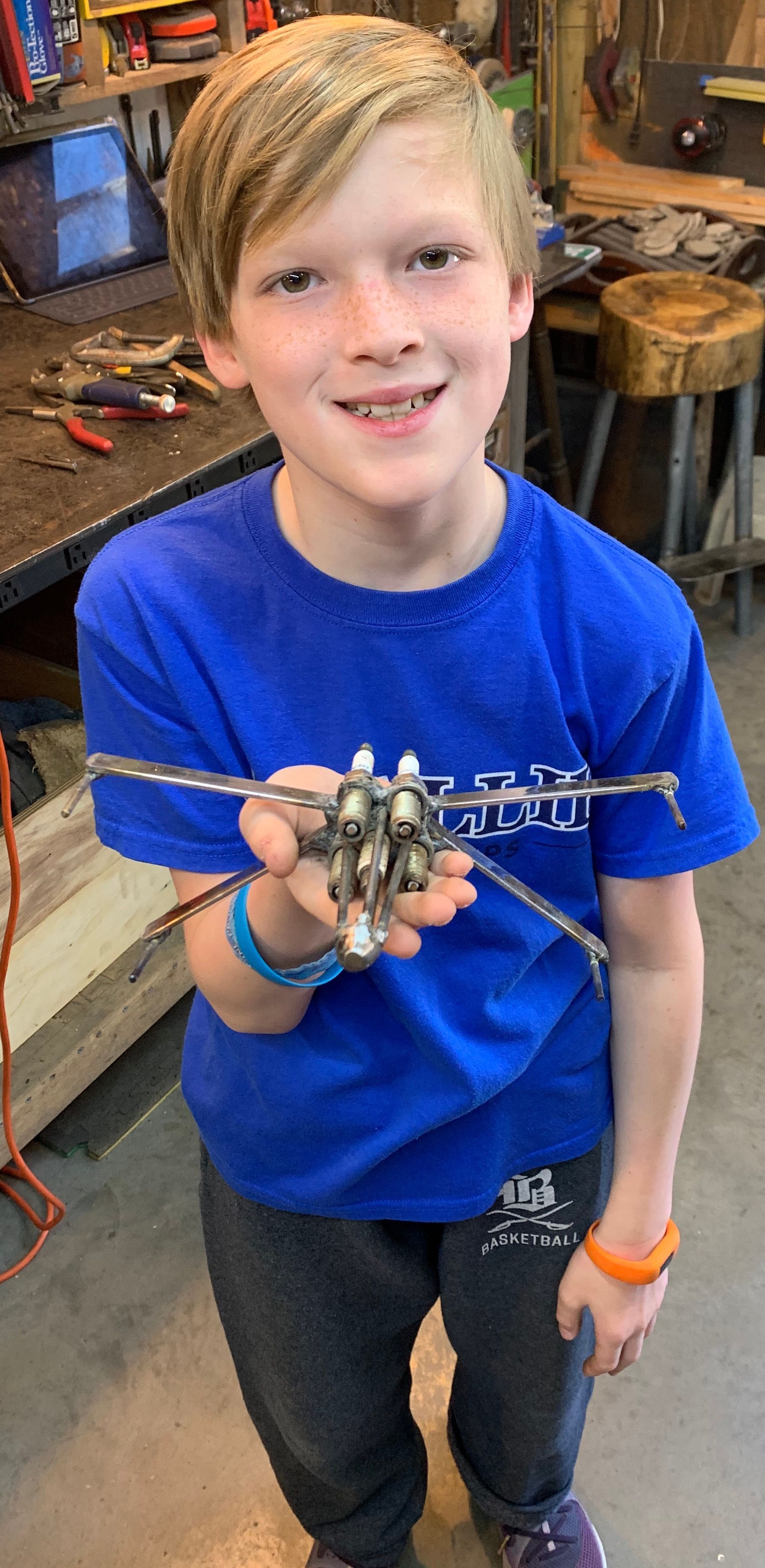 A young boy in a blue shirt is holding a toy helicopter in his hands.